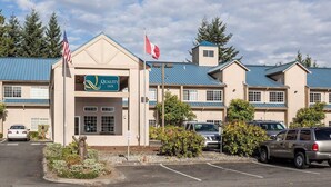 A hotel with a sign reading 'Quality Inn,' a parking lot, and a flagpole with flags. - Quality Inn Tulalip - Marysville (Marysville)