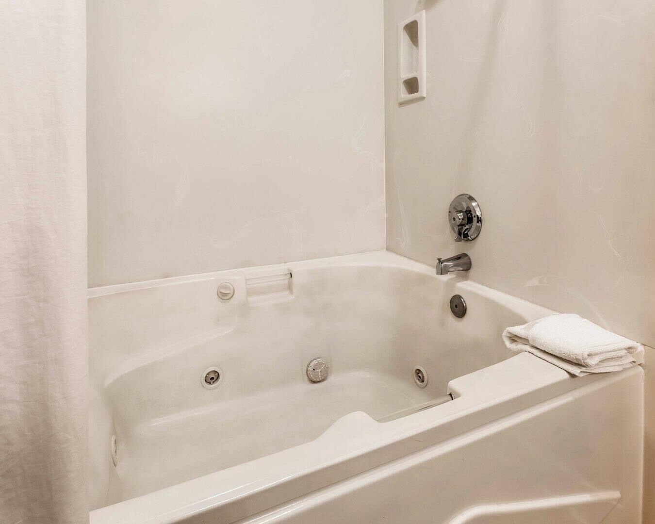 A white bathtub with a showerhead, a faucet, and a towel.