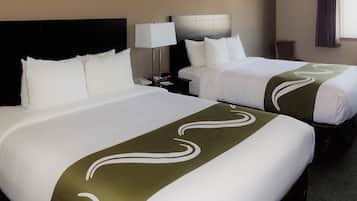 Une chambre d’hôtel avec deux lits, une table de chevet avec une lampe et une petite table.