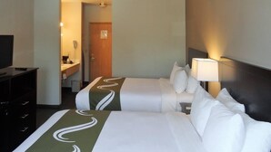 A hotel room with two beds, a desk, a chair, a lamp, a TV, and a bathroom visible through an open door. - Quality Inn Tulalip - Marysville (Marysville)