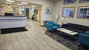 A reception area with a counter, blue chairs, a sofa, and a carpeted floor. - Quality Inn Tulalip - Marysville (Marysville)