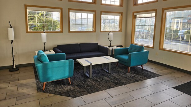 A room with a dark sofa, two teal armchairs, a small white table, and a floor lamp. - Quality Inn Tulalip - Marysville (Marysville)