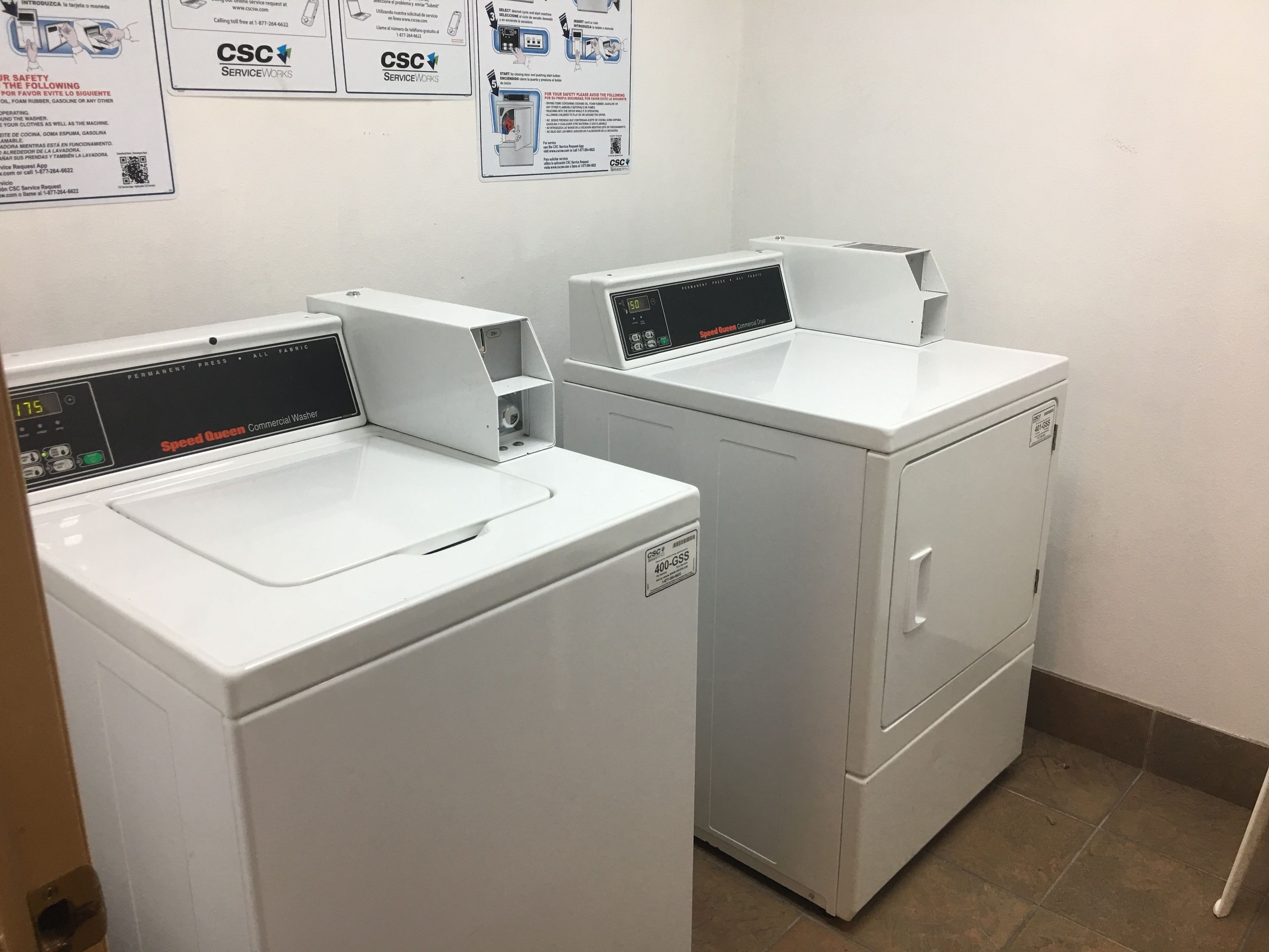 Two front-loading commercial washers with digital displays, labeled 'CSC ServiceWorks'.