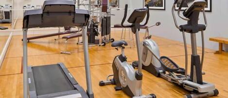 A gym with a treadmill, stationary bikes, and weight machines.
