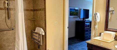 A hotel bathroom with a shower, a towel rack, a sink, and a mirror.