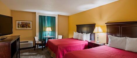 A hotel room with two beds, a TV, a desk, and a chair.