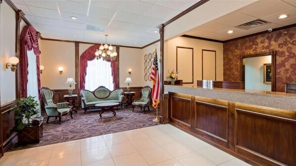 A hotel lobby with a reception desk, seating area with a sofa and chairs, a chandelier, and an American flag. - Osage Creek Lodge (Eureka Springs)