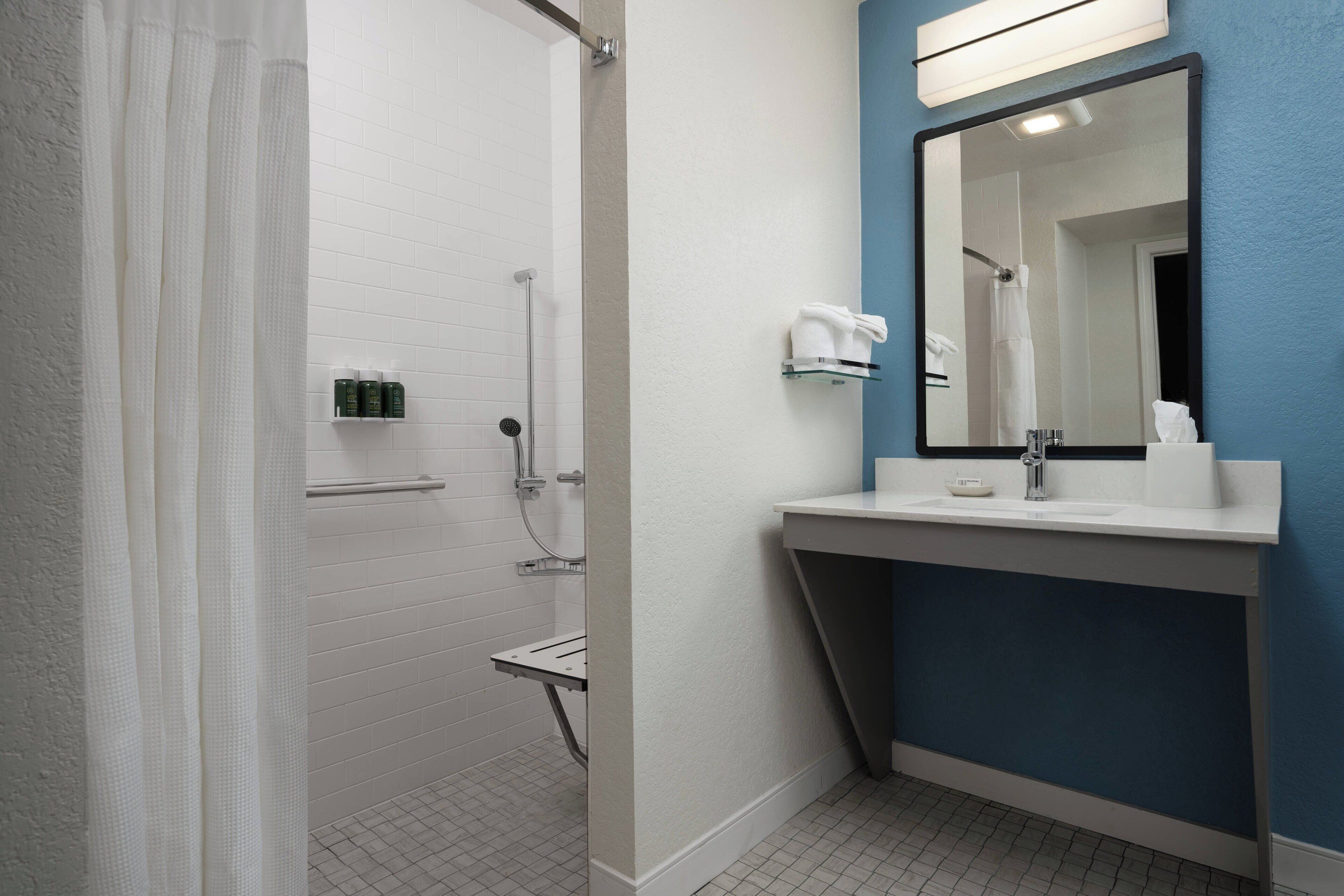 Un baño moderno con ducha, lavamanos y espejo.