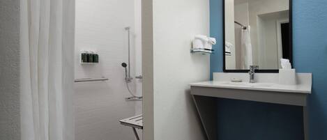 Un baño moderno con ducha, lavamanos y espejo.