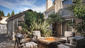 A patio with four striped chairs and a stone fire pit.