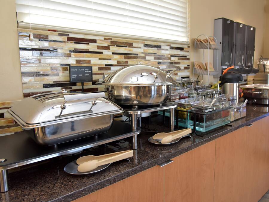 A buffet setup with various food containers and serving utensils.