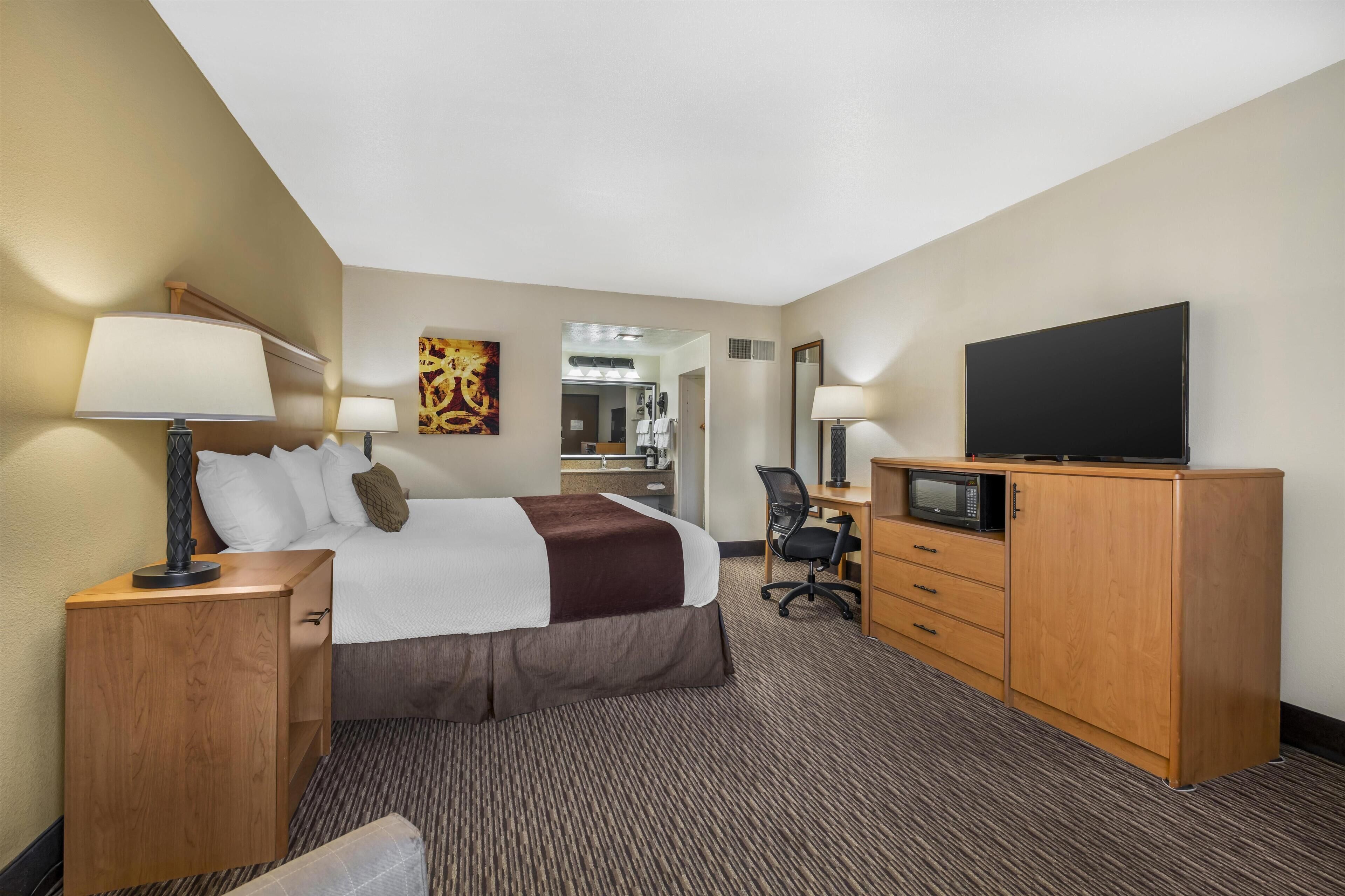 A hotel room with a bed, a desk, a TV, and a microwave.