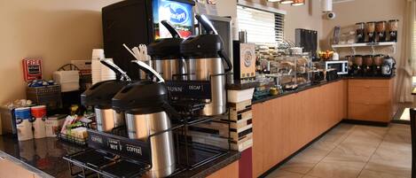Una estación de café con varias máquinas de café, un extintor y distintos recipientes para café.