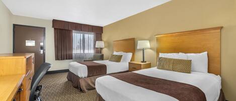 A hotel room with two beds, a desk, and a chair.
