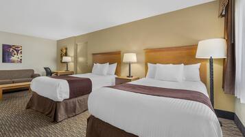 A hotel room with two beds, a sofa, a desk, and a lamp.