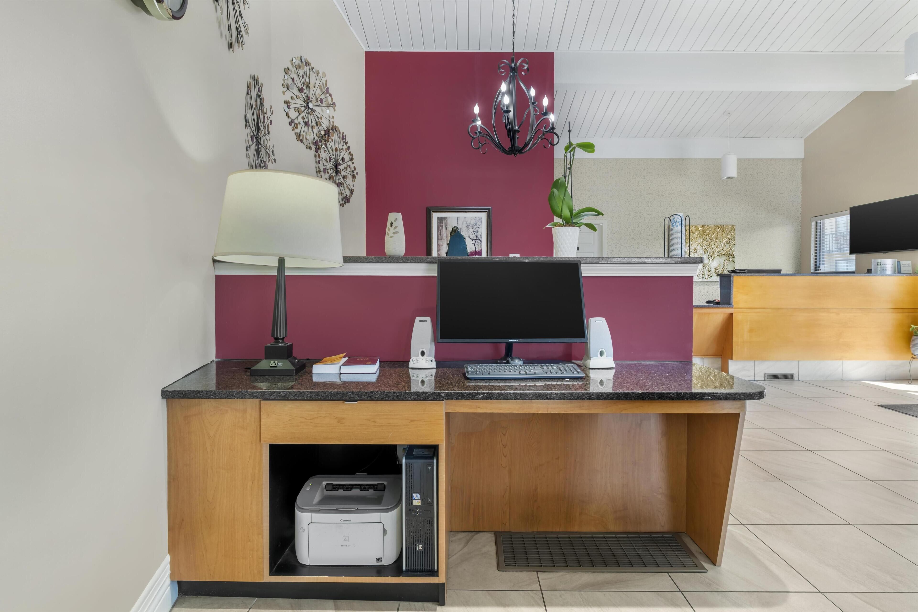 A modern reception desk with a computer, printer, and decorative items.