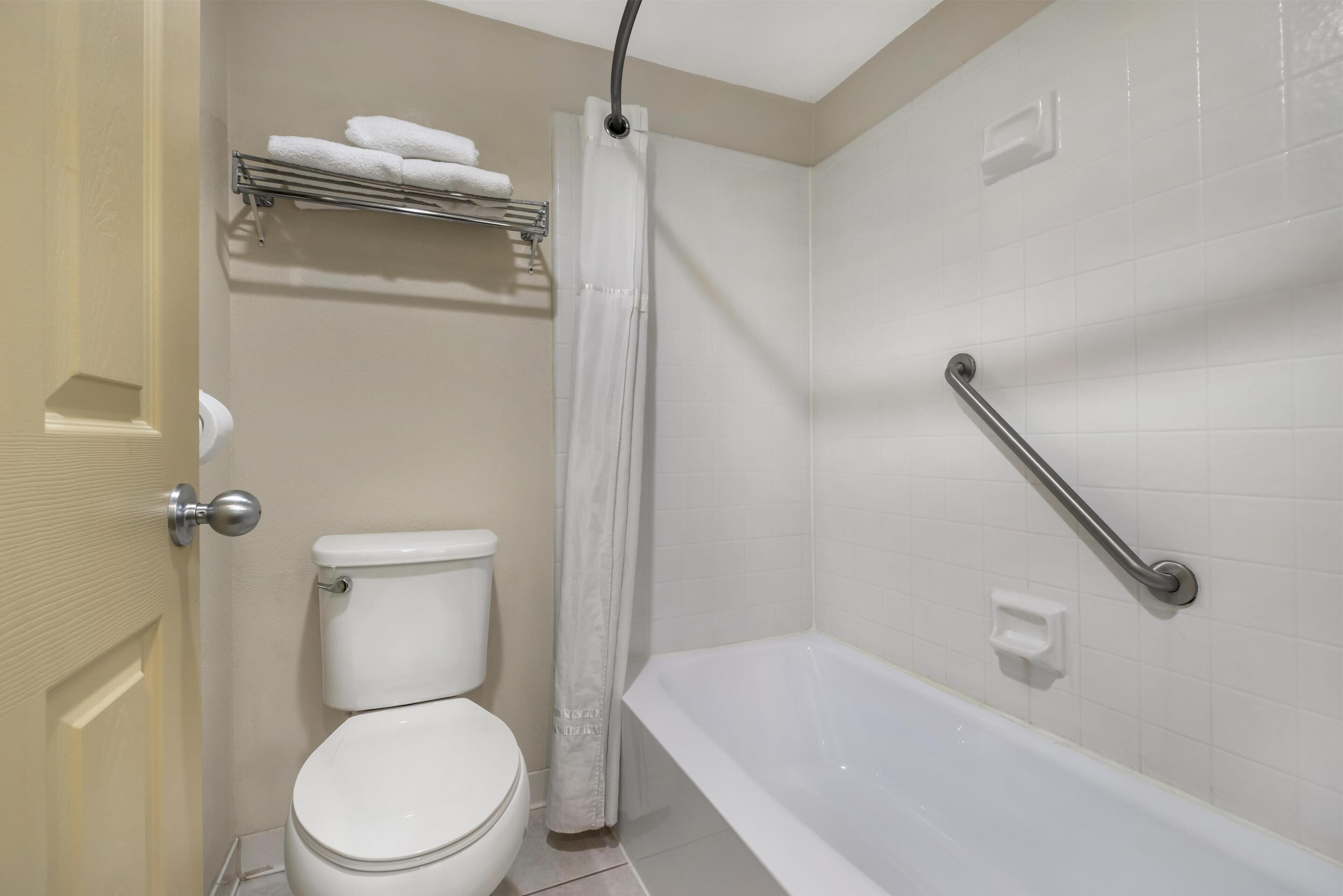 A bathroom with a toilet, a bathtub, a shower curtain, and a towel rack.