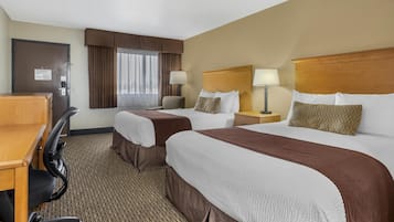 A hotel room with two beds, a desk, and a chair.