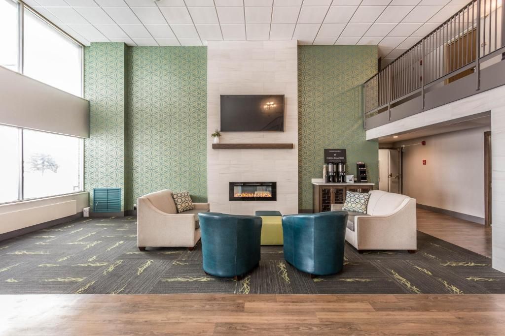 A lobby with a fireplace, seating area, and a staircase.