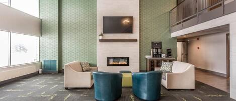 A lobby with a fireplace, seating area, and a staircase.