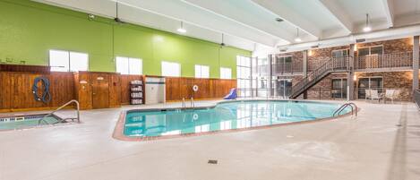 Una piscina interior con cubierta de madera y pared de ladrillo.