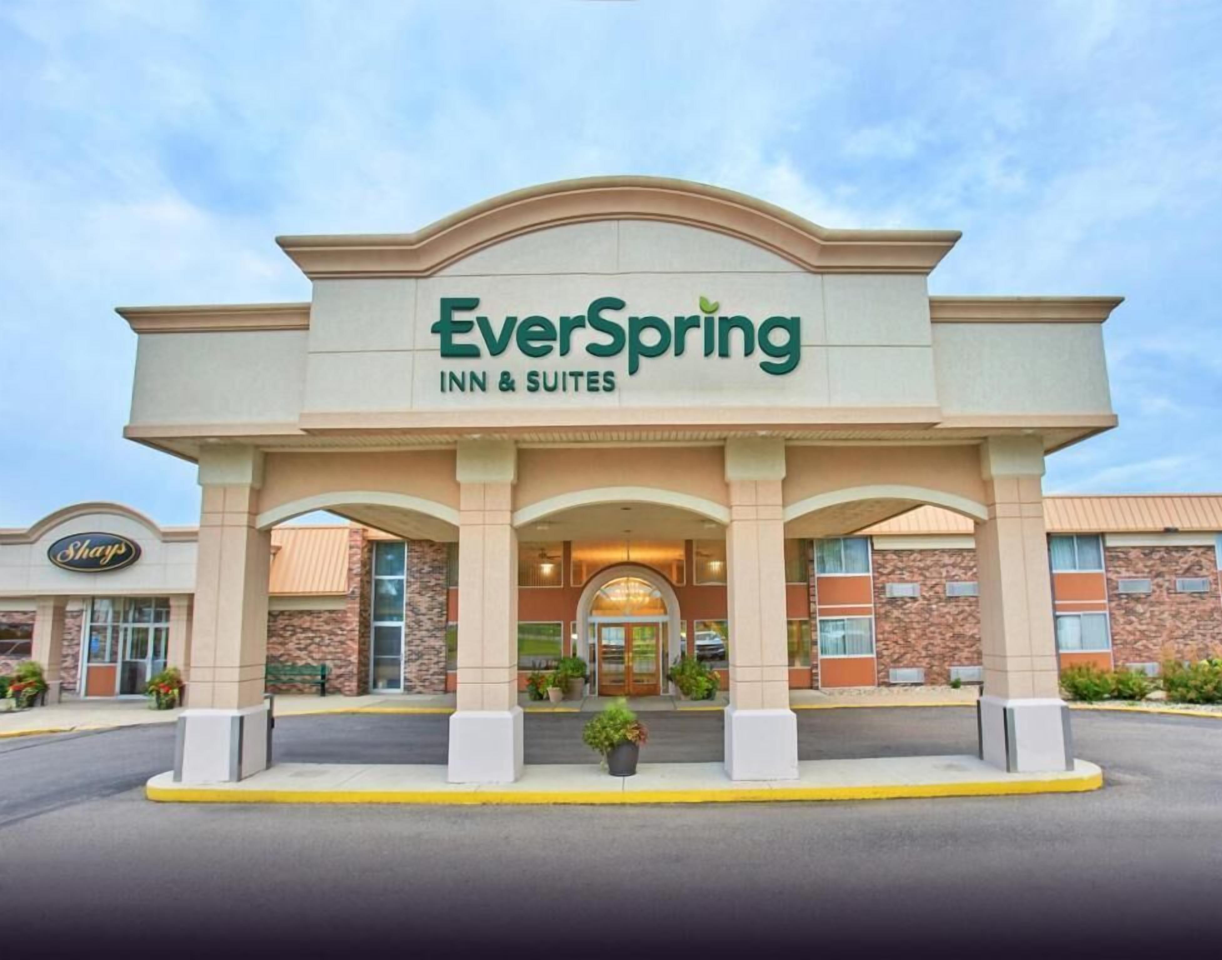 Un hôtel EverSpring Inn & Suites avec une entrée bien visible, une enseigne de la pharmacie Shoppers Drugstore et un ciel dégagé.