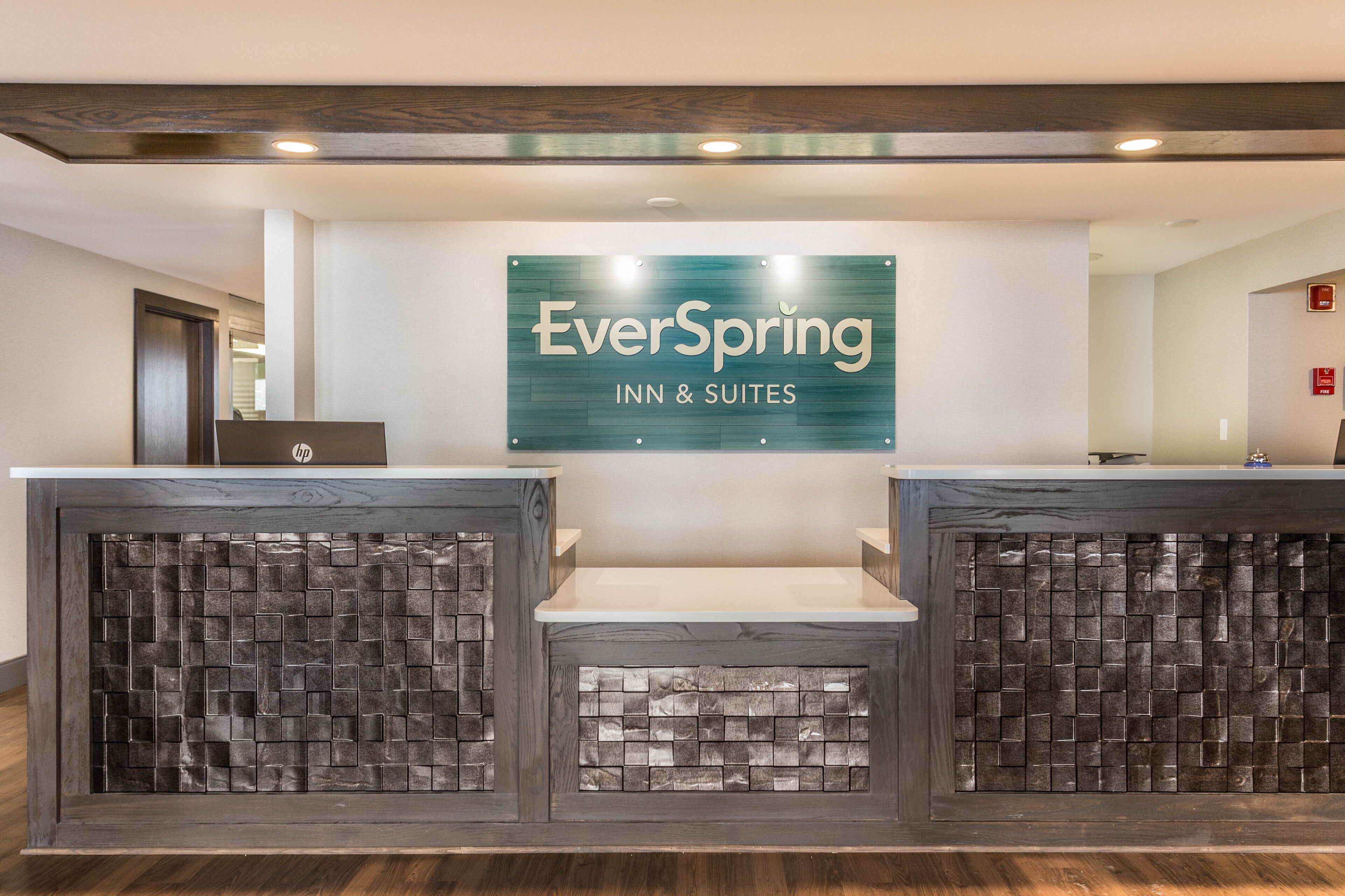 Ein Empfangsschalter mit einem Schild für EverSpring Inn & Suites, gestaltet im modernen Stil mit einer Steinauffahrt und einer einladenden, freundlichen Atmosphäre.
