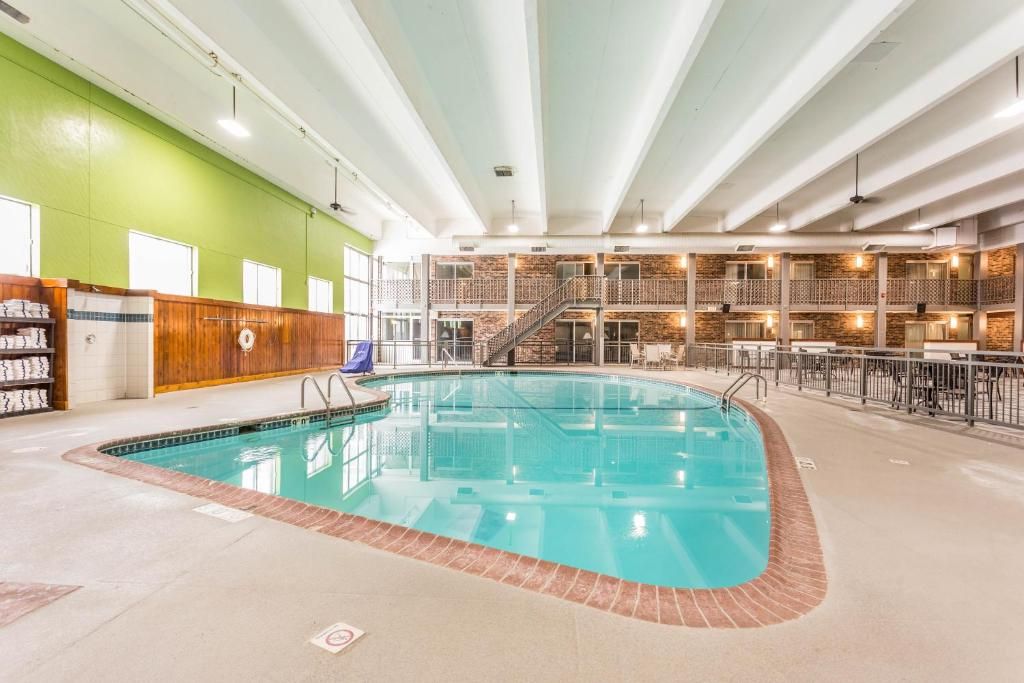Une piscine intérieure bordée de briques, un comptoir d’accueil en bois et un balcon à plusieurs niveaux doté de rampes.
