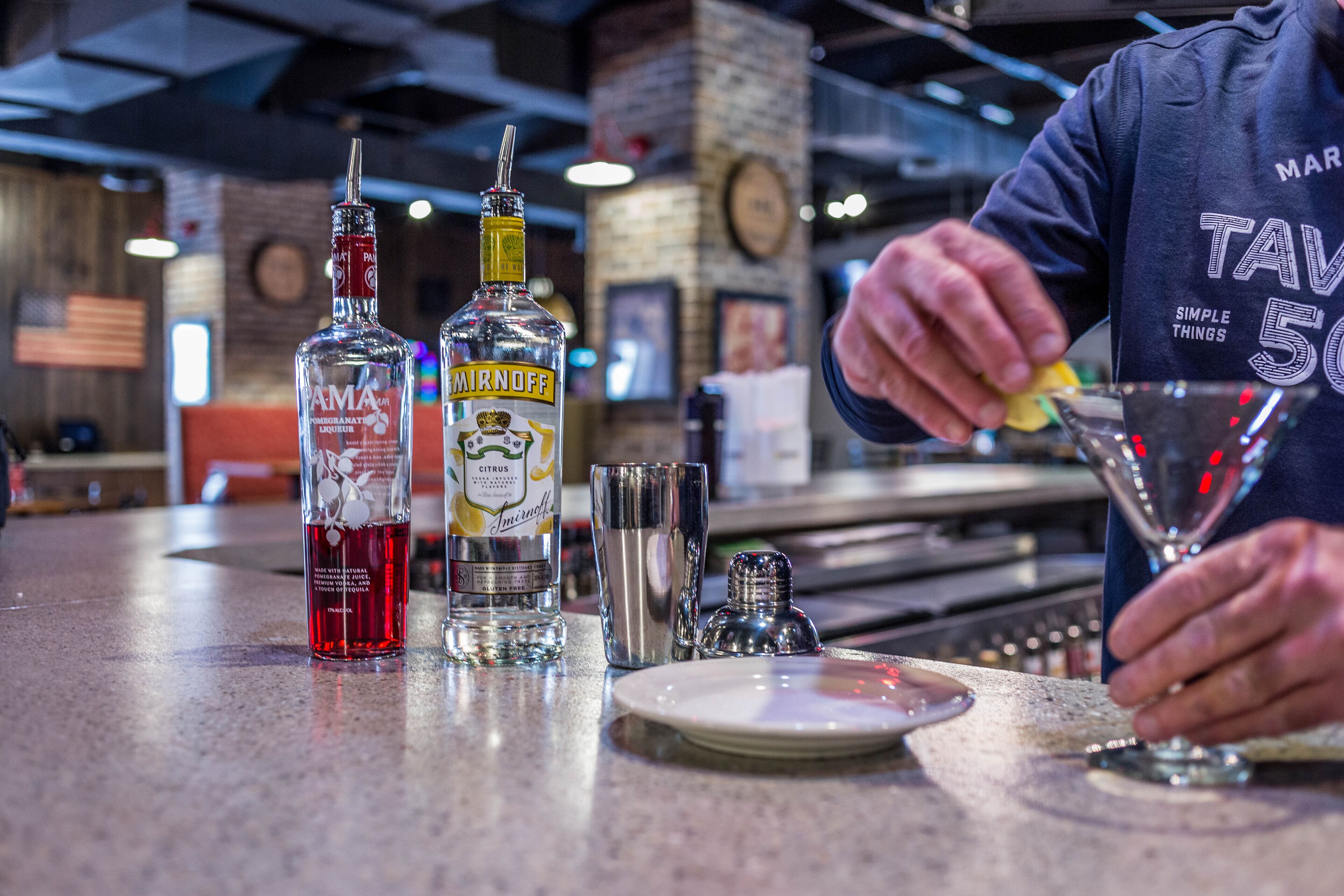 Un bar con botellas de licor Amita y Mirnoff, una copa de martini y utensilios de bar sobre una encimera.