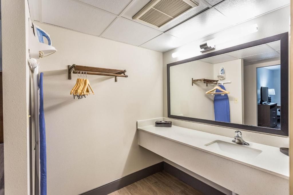 Un baño de hotel con un espejo grande, un lavamanos y un perchero para toallas.
