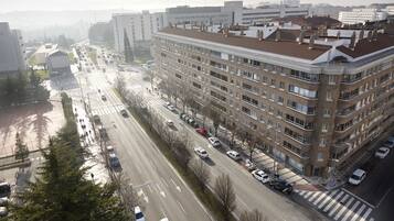 A multi-story building with a flat roof and rectangular windows, located adjacent to a wide road with multiple lanes and vehicles.