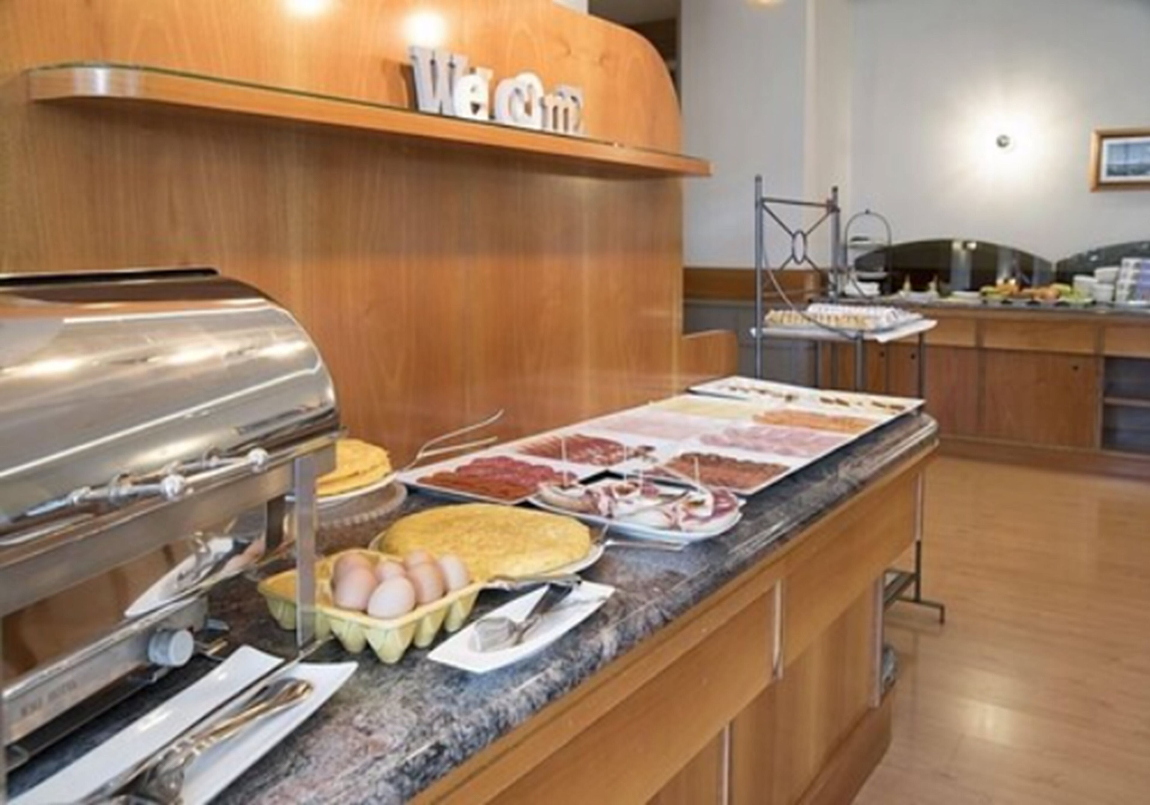 A buffet area with a variety of food options, including eggs, meats, and a griddle.
