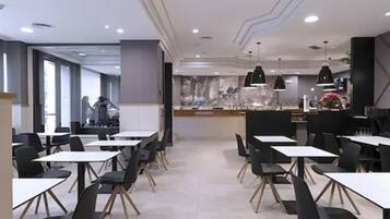 A modern dining area with tables and chairs, a counter, and a decorative wall.