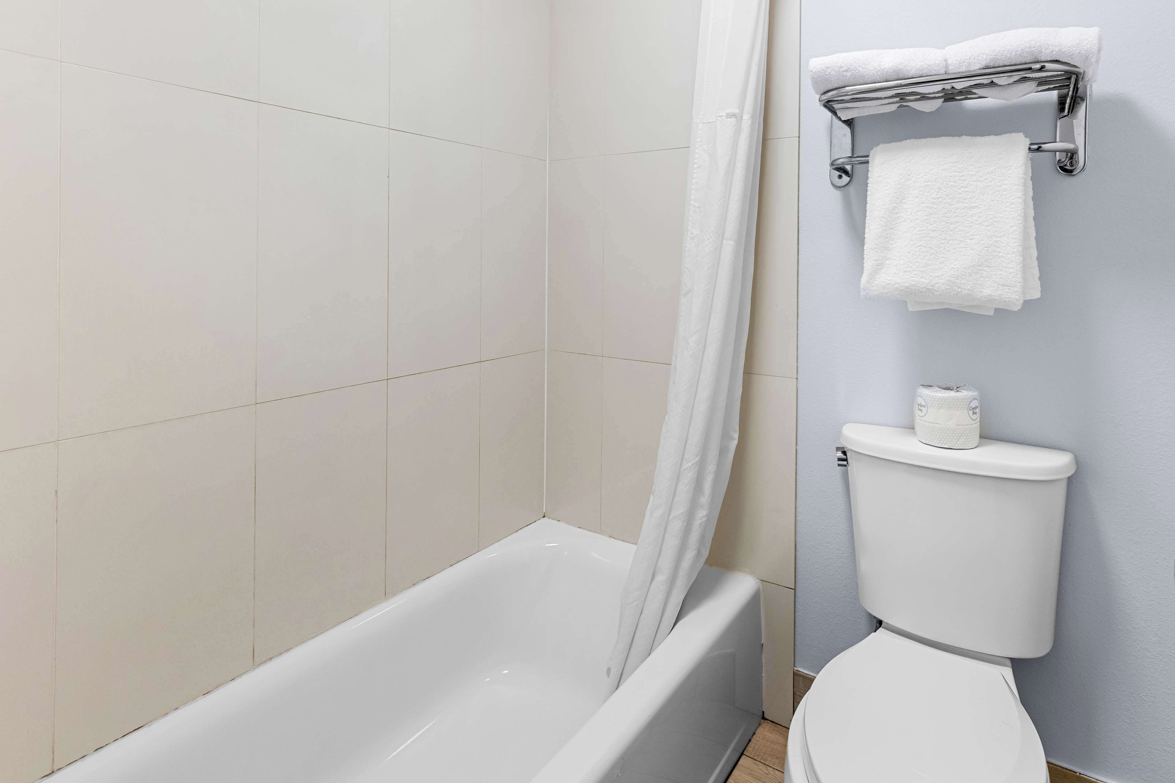 A bathroom with a bathtub, toilet, and towel rack.
