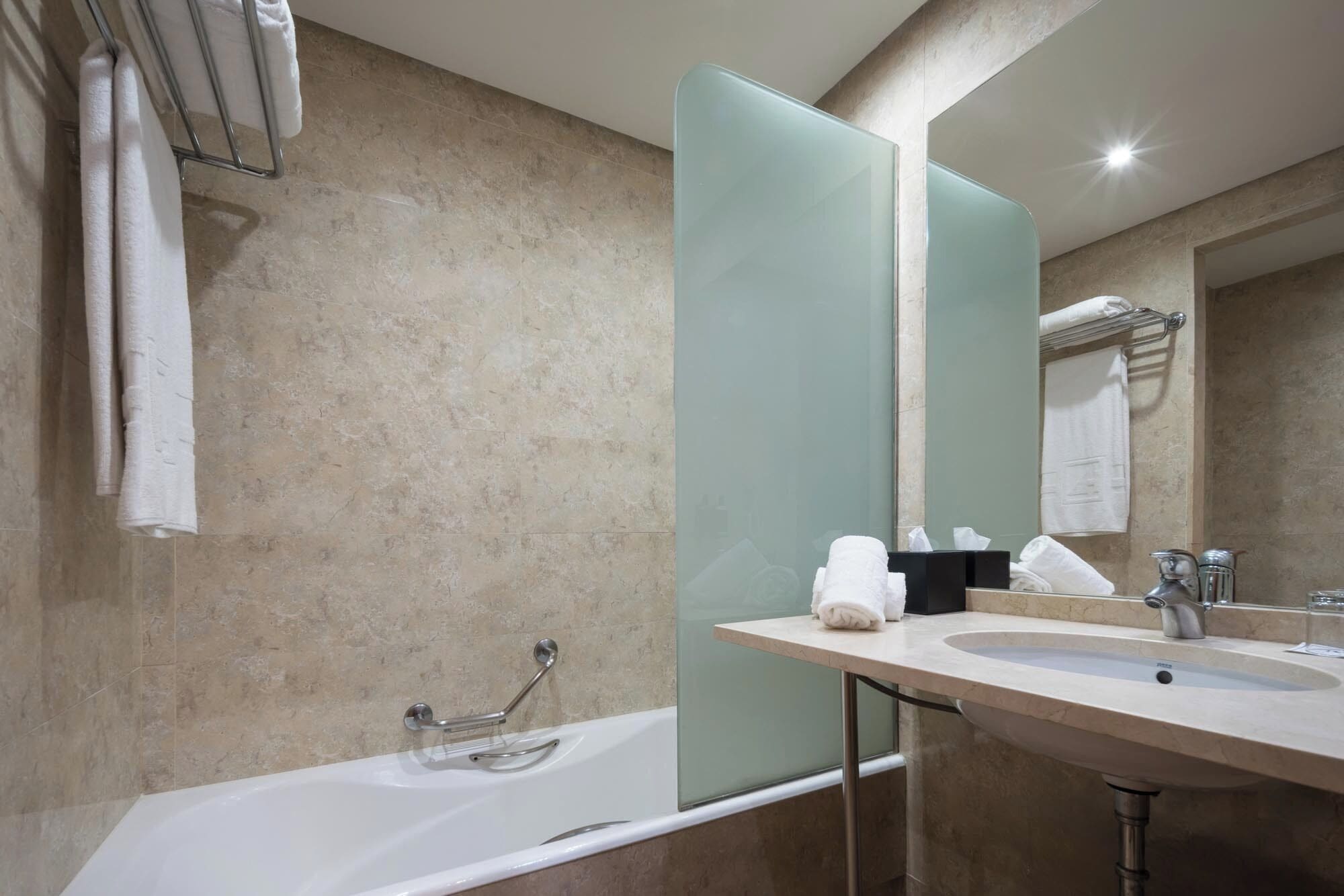 A modern bathroom with a bathtub, a sink, and a large mirror.