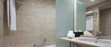 Un baño moderno con bañera, lavabo y un espejo grande.
