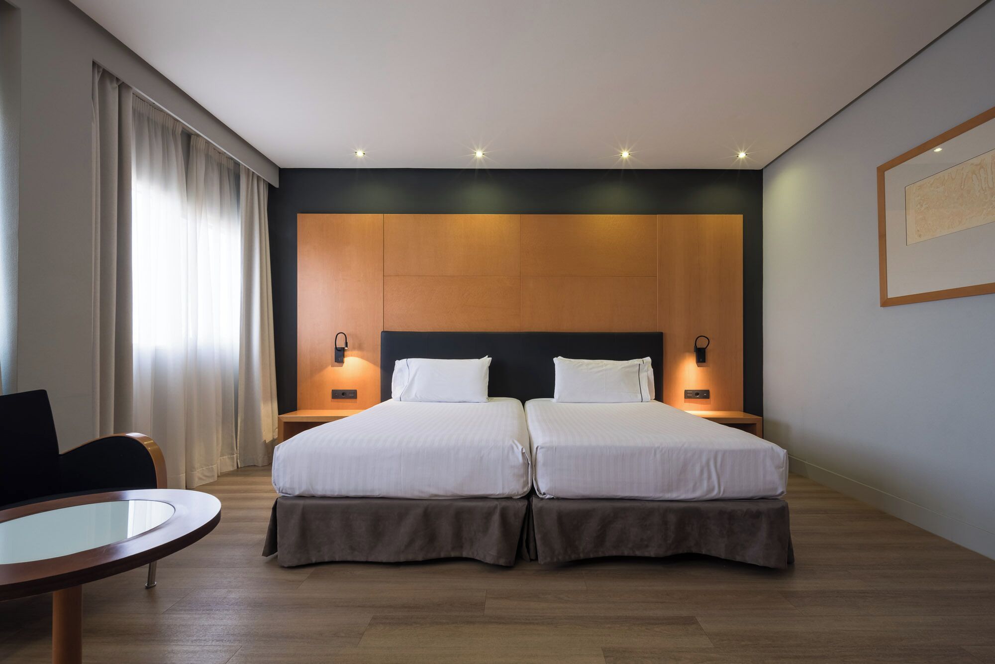 Ein Hotelzimmer mit zwei Betten, einem kleinen Tisch und einem Stuhl.