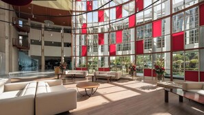 A spacious lobby with a high ceiling, large windows, and modern furniture. - Eurostars Al-Ándalus Palace (Seville)