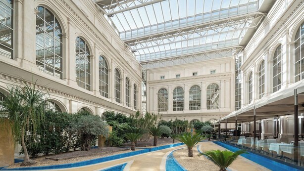 A spacious indoor atrium with a central pool, surrounded by lush greenery and classical architecture. - Eurostars Al-Ándalus Palace (Seville)
