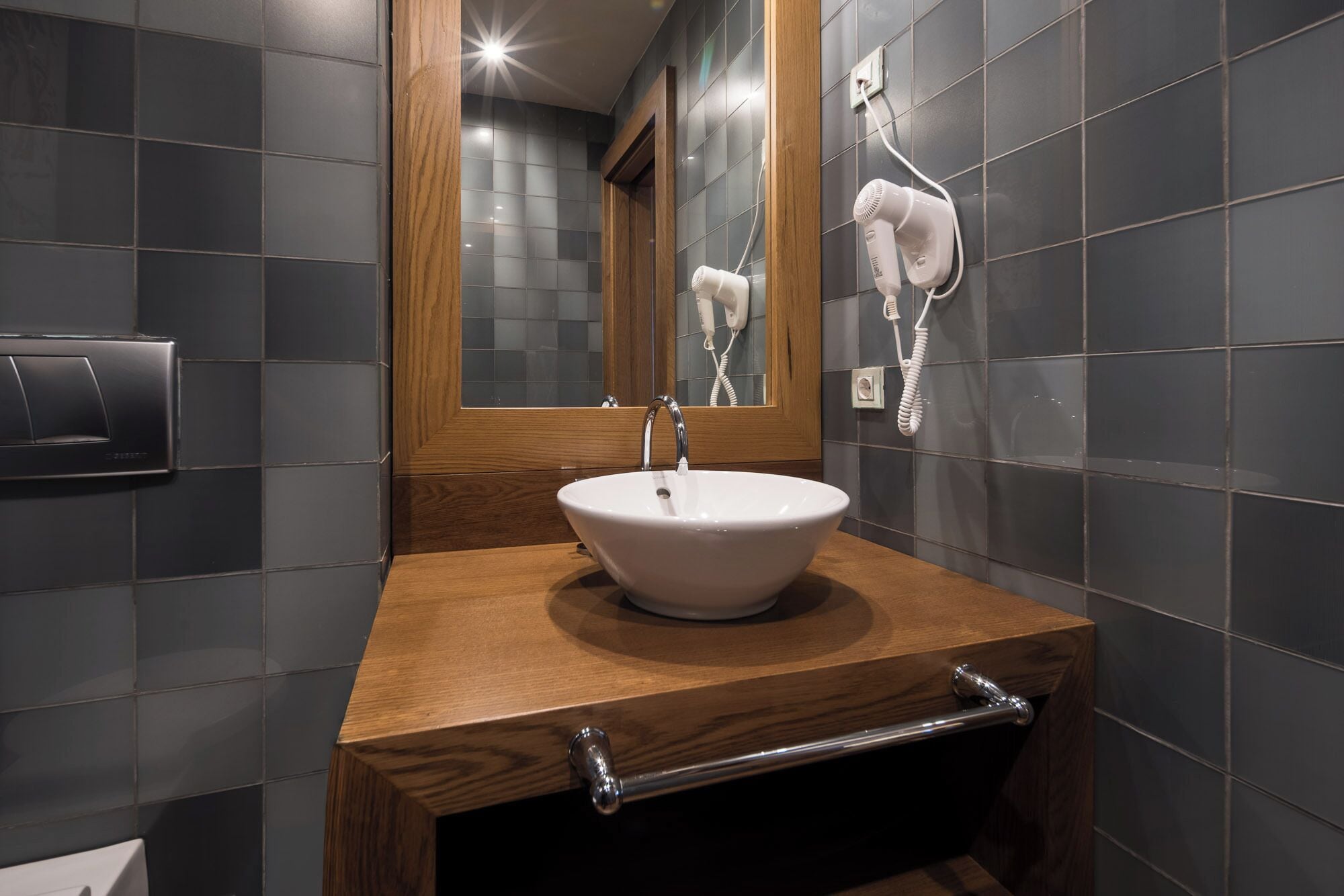 Un baño con tocador de madera, un lavabo blanco y un espejo.