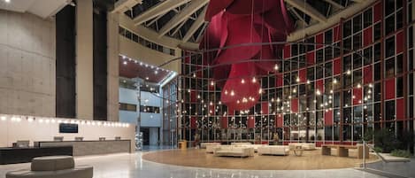 A spacious lobby with a high ceiling, large windows, and a central seating area.