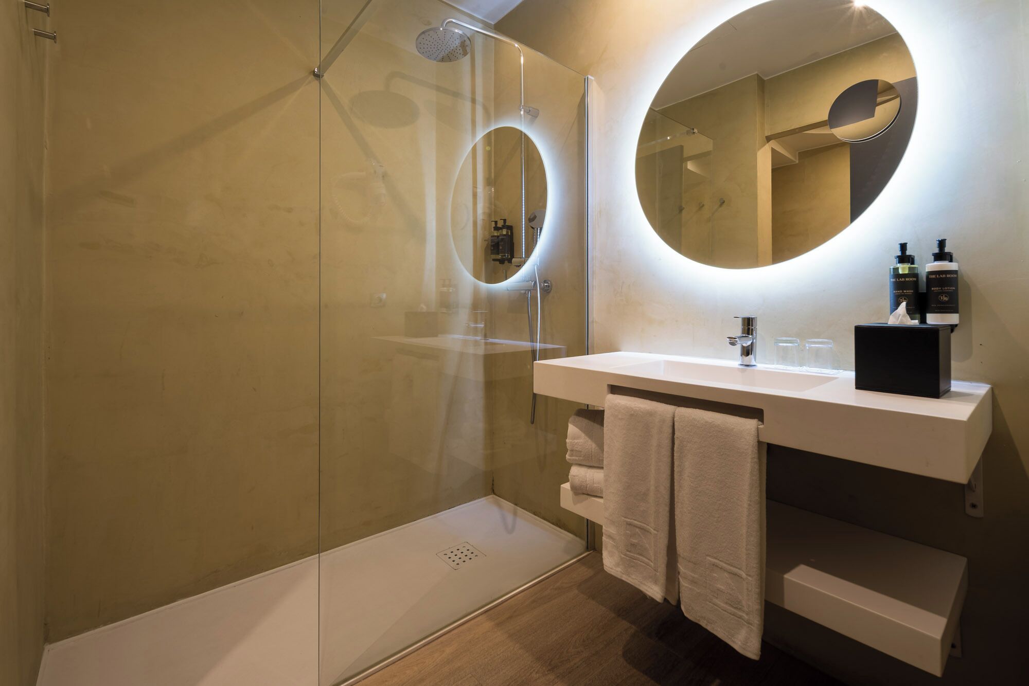 Un baño moderno con ducha envuelta en vidrio, un lavabo blanco y un espejo grande.