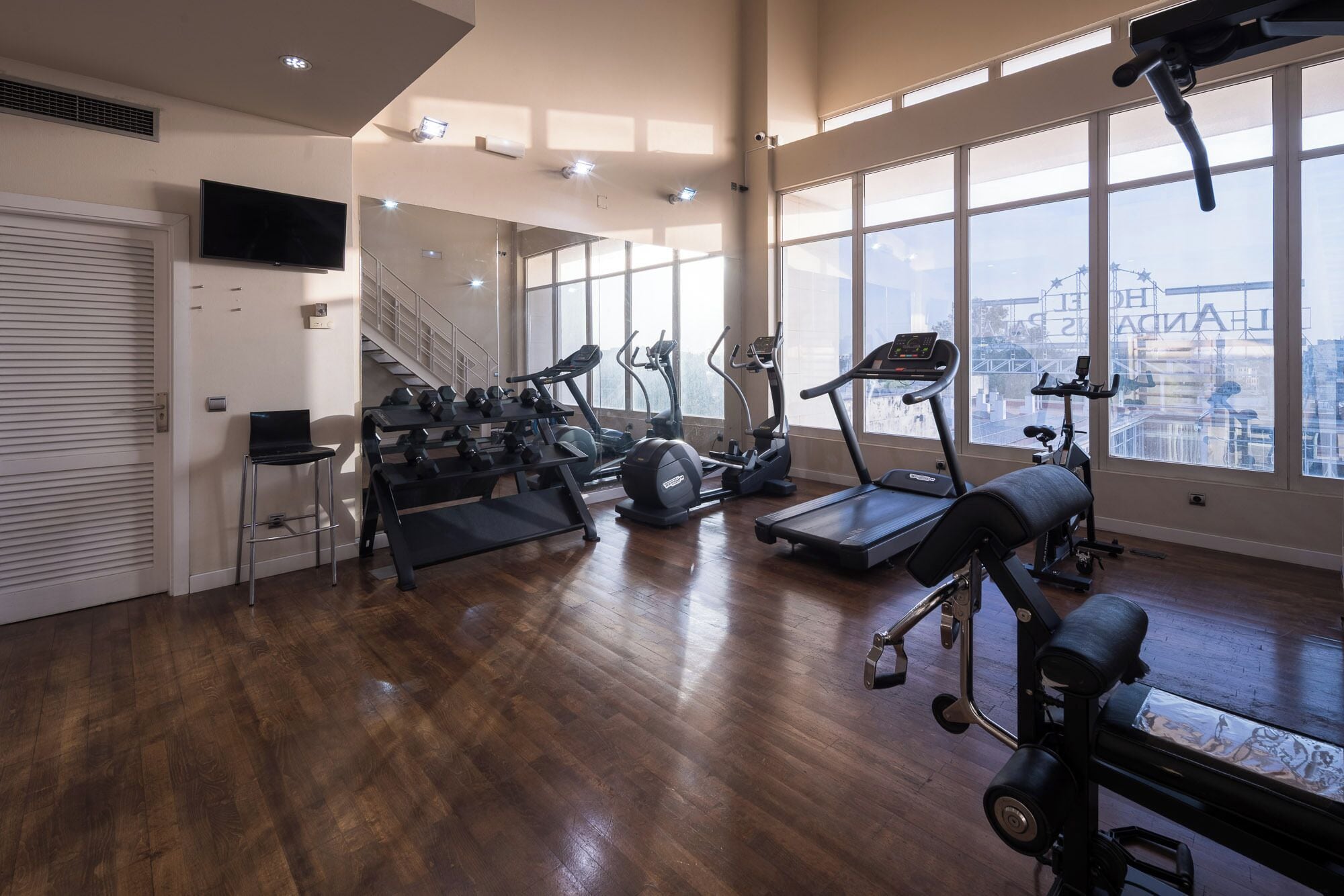 Un gimnasio amplio con cintas de correr, elípticas y un soporte para pesas.