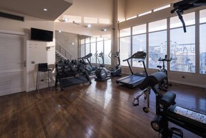 Un gimnasio amplio con cintas de correr, elípticas y un soporte para pesas.