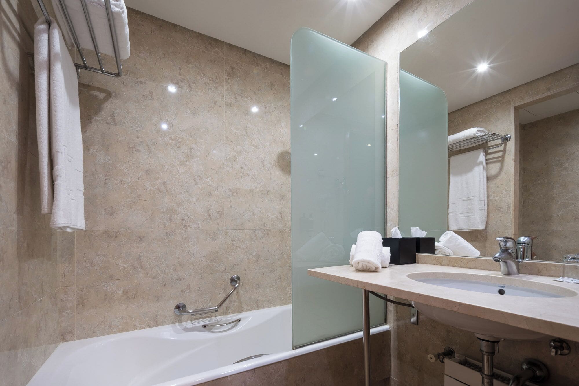 Un baño moderno con bañera, cabina de ducha de vidrio, lavabo y un espejo grande.
