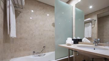 Un baño moderno con bañera, cabina de ducha de vidrio, lavabo y un espejo grande.