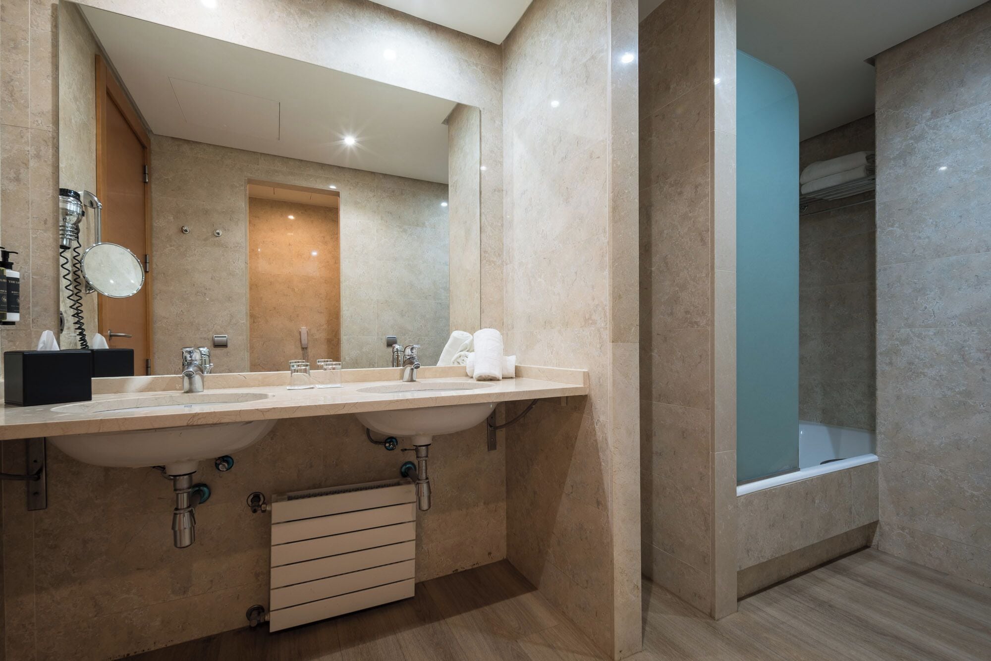 Ein modernes Badezimmer mit zwei Waschbecken, einem großen Spiegel und einer begehbaren Dusche.