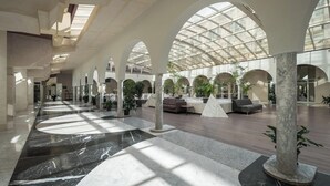 A spacious lobby with high ceilings, arched columns, and a central seating area. - Eurostars Al-Ándalus Palace (Seville)