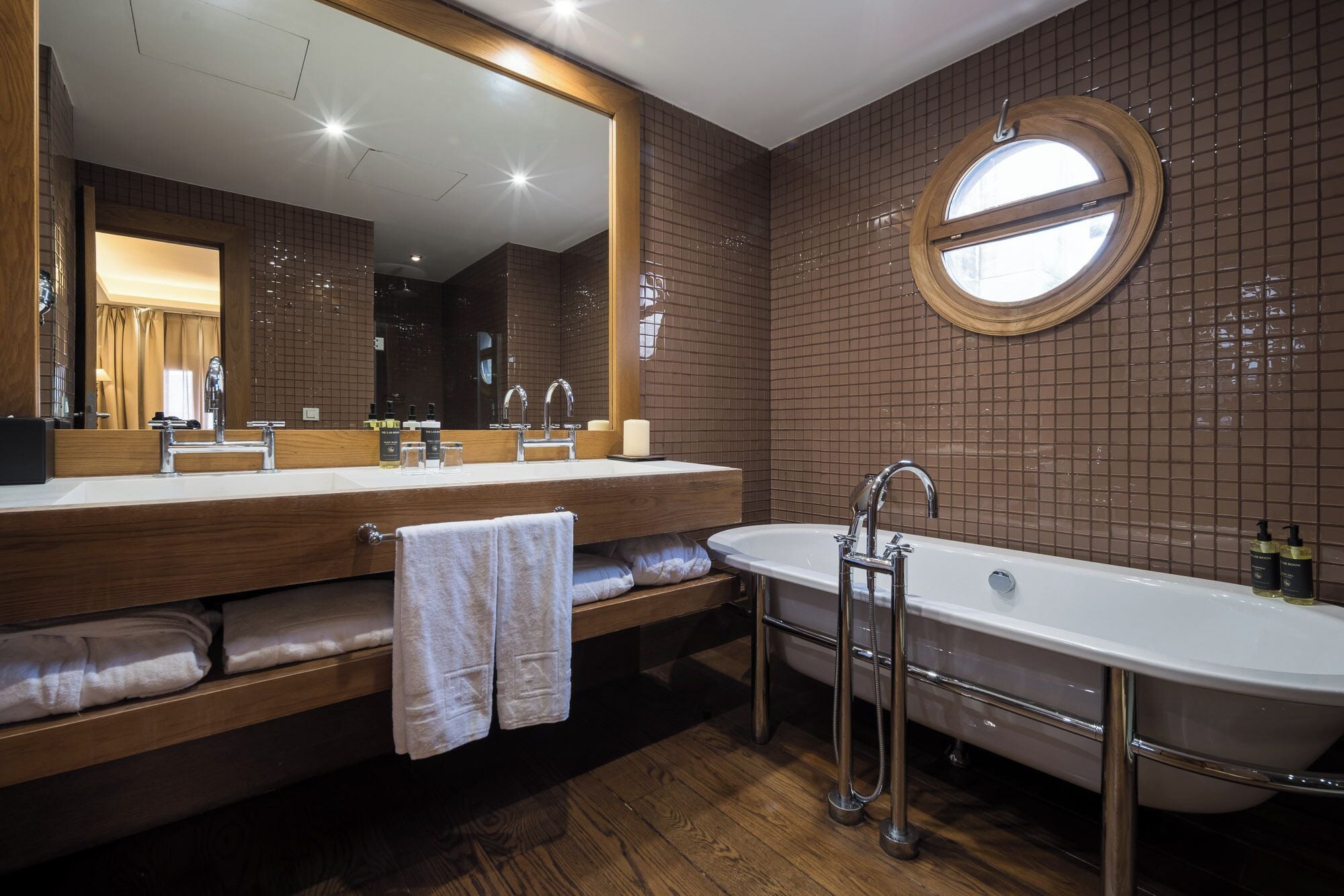 Un baño moderno con un espejo grande, una bañera independiente y un tocador con lavamanos.