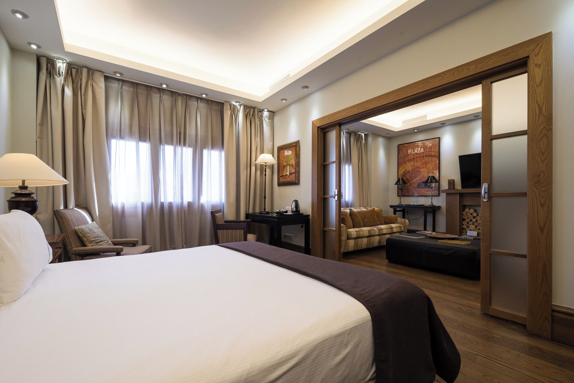Una habitación de hotel con una cama grande, un escritorio con lámpara, un sofá y un televisor.
